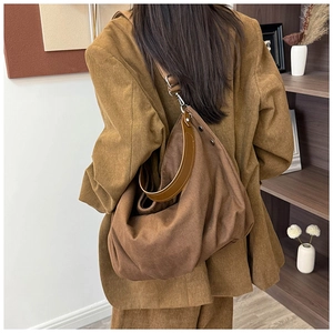 Detail of dark brown canvas hobo bag with leather handles shown on a model