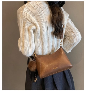 Detailansicht einer braunen Vintage-Lederbeuteltasche mit Pompon und gewebtem Gurt