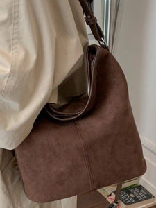 Large dark brown suede tote bag with retro shoulder design worn by a female model