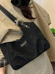 Borsa a spalla in nylon nero con logo dorato abbinata a un trench coat kaki