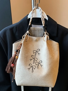 Minimale beige suède emmertas met vlinderborduursel en kwastje als detailversiering