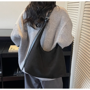 Detailed view of a black oversized matte hobo bag on model with adjustable strap