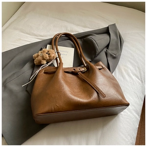 Close-up of vintage brown faux leather tote with metal buckle and plush bear charm