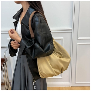 Detail of khaki canvas tote bag with brown strap styled with a black leather jacket