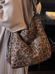 Detail view of leopard print tote bag with brown fabric strap and small leather patch