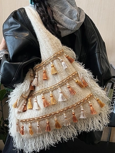Ethnic knit tote bag with boho tassels and feather trim shown on model shoulder