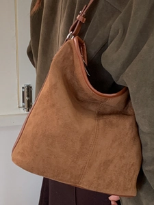 Brown suede hobo tote bag with leather trim worn on the shoulder for a casual commuter look
