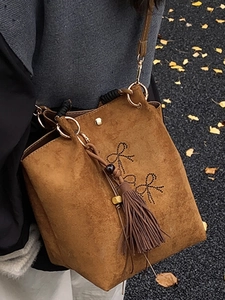 Bruine suède bucket bag met strik uitsnijdingen en kwastjes in Chinese minimalistische stijl