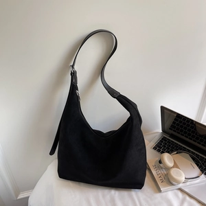 Detail of black suede tote bag with silver zipper and spacious bottom in home office setting