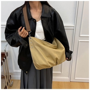 Detail of khaki canvas tote featuring wide brown strap and silver metal adjustment buckle