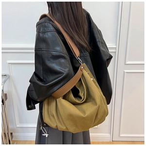 Detail of vintage olive green canvas tote bag with wide brown shoulder strap and metal hardware