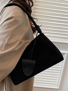 Minimalistische schwarze matte Unterarmtasche mit Knotendetail auf beigem Trenchcoat