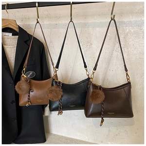 Drei minimalistische Leder-Halbmondtaschen in Braun, Kaffee und Schwarz mit Plüsch-Anhängern