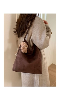 Détail d'un sac cabas en daim marron foncé avec un charmant ours en peluche sur un mannequin