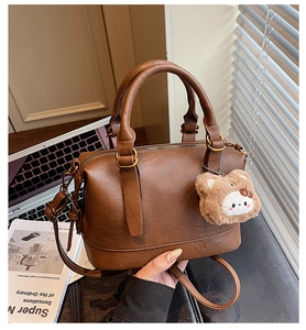 Detail view of brown vintage PU leather handbag with plush charm and long shoulder strap