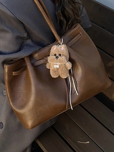 Vintage large dark brown suede tote bag with plush charm on a grey blazer model