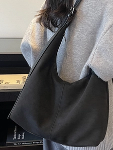Minimalist black matte suede hobo bag with adjustable strap and vertical seam design