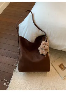 Détail d'un grand sac cabas en daim marron avec un joli pendentif chien en peluche