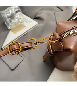 Detail of adjustable leather strap and polished gold hardware on brown crossbody bag