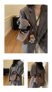Close-up of brown pebbled leather bucket bag with metal lock and cute teddy bear charm