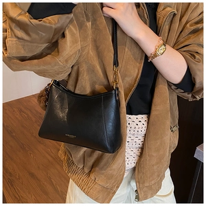 Detail der schwarzen Leder-Beuteltasche mit goldener Hardware und Plüsch-Anhänger