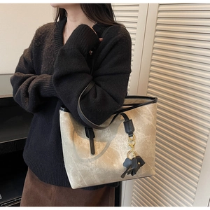 Detail of grey marble pattern tote bag with black straps and a small elephant charm