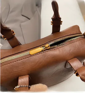 Detailed close-up of the smooth golden zipper and leather texture on a brown handbag