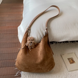 Detail view of brown suede hobo tote bag texture with a cute teddy bear plush charm
