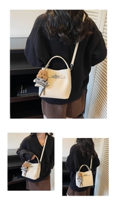 Detailed view of cream leather bucket bag with metal lock closure and cute teddy charm