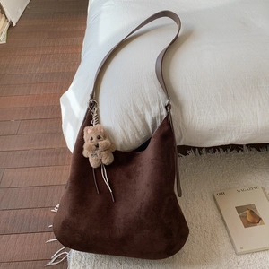 Macro shot of dark brown suede tote bag showing texture and cute plush puppy charm