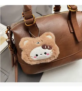 Close-up of vintage brown pebble leather handbag with a cute plush cat charm and gold hardware