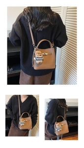 Brown lychee leather bucket bag detail with a cute teddy bear charm and silver buckle