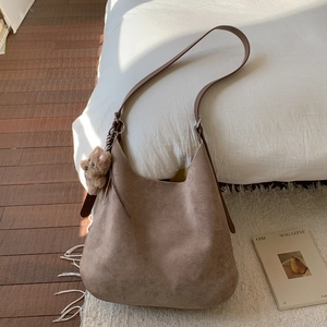 Detail of brown suede tote bag with adjustable strap and cute teddy bear charm