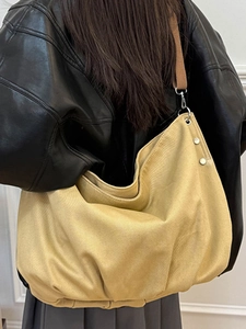 Minimalist khaki canvas tote bag with wide brown strap worn by a model in casual style