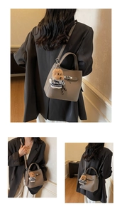 Detail view of taupe leather bucket bag with silver twist lock and cute bear charm pendant