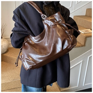 Close-up of the oil wax leather texture and side drawstring detail on the tote bag