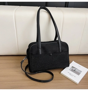 Détail du sac à bandoulière noir avec cristaux argentés sur une surface en bois