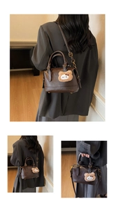 Detail of vintage dark brown pillow bag with cute plush bear charm and metallic zipper