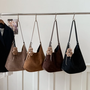 Detail view of four suede hobo tote bags in various earthy tones with plush bear charms