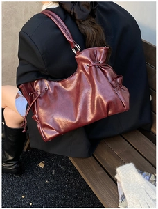 Detail of burgundy PU leather tote bag featuring drawstring pleats and side pockets