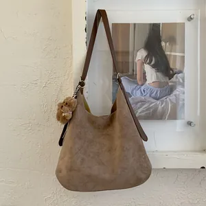Detail of coffee suede tote bag with brown leather straps and a plush bear pendant
