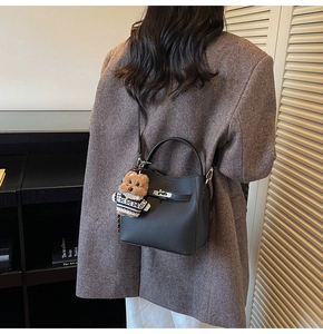 Close-up of black lychee grain leather bucket bag with silver lock and teddy bear charm