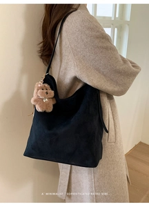 Détail d'un grand sac cabas en daim noir avec un joli porte-clés en forme d'ours en peluche