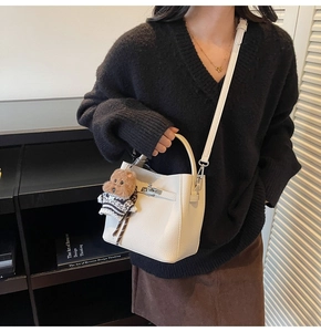 Detail of cream bucket bag with silver twist lock and cute teddy bear charm on strap