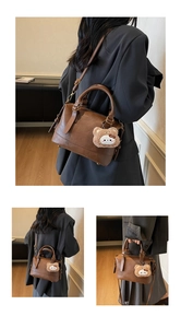 Detail view of brown vintage pillow bag with crossbody strap and cute plush bear charm