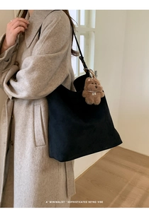 Détail d'un sac seau en daim noir avec un joli pendentif ours en peluche marron