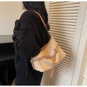 Détail du sac hobo en daim kaki avec lanières en cuir marron porté par un mannequin