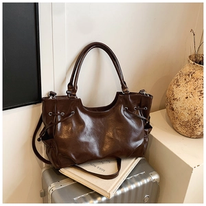 Detail of dark brown oil wax leather tote bag with silver hardware and side drawstrings