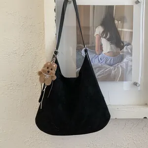 Close-up of black suede tote bag with a cute brown teddy bear plush charm and pearl necklace