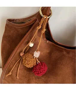 Détail du sac seau en daim marron avec breloque artisanale en crochet et perles en bois